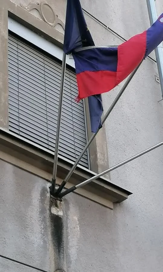 Zastava, zavita okrog droga, in madež na fasadi pod nosilcem